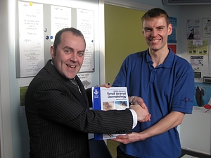 Animalcare representative, Ronnie Cottrell presents a manual to John Goacher at A & G Vets, Bonnybridge